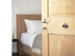ein Schlafzimmer mit einem Bett mit weißen Laken und einer Holztür in der Unterkunft Marktplatz 10 in Kaltern