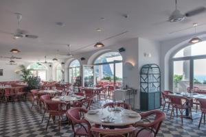 a restaurant with tables and chairs and windows at Il Capri Hotel in Capri