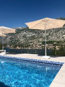 a swimming pool with an umbrella and a mountain at Apartments Seaview Estate Radovic in Kotor