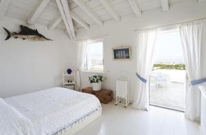 a white bedroom with a bed and a large window at Villa dei Tramonti in Porto Rotondo