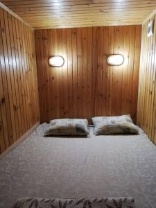 a bedroom with wooden walls and a bed with two pillows at Rodina Hotel in Odesa