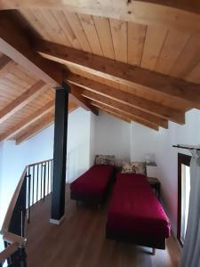 a bedroom with a red bed and a wooden ceiling at Cascina Teresina in Veleso