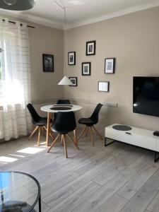 ein Wohnzimmer mit einem Tisch und Stühlen sowie einem TV in der Unterkunft Apartament Młociny in Warschau