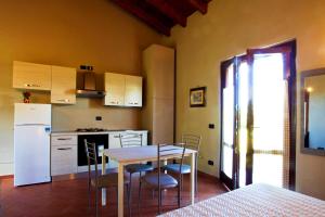La cuisine est équipée d'une table, de chaises et d'un réfrigérateur blanc. dans l'établissement B&B Cascina Quaderna, à Castenedolo