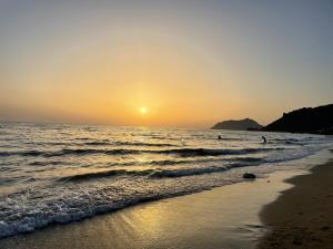 a beach at sunset with people in the water at Anastasia’s Apartment in Sinarádes +9 photos