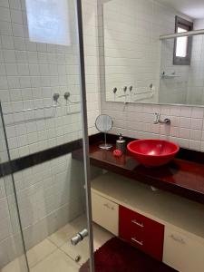 ein Badezimmer mit einem roten Waschbecken und einem Spiegel in der Unterkunft Apartamentos no Solar Pipa in Pipa