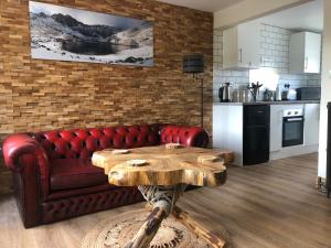a living room with a red couch and a wooden table at Honey lodge in Caeathro