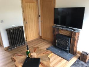 a living room with a television and a table with a bottle of wine at Honey lodge in Caeathro