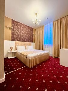 Sergeev Hotel في نيكولايف: غرفة نوم بسرير كبير وسجادة حمراء