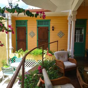 un porche de una casa con una silla y flores en COZY NEST en Guayama