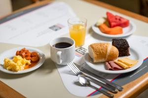a table with plates of breakfast food and a cup of coffee at Rede Andrade Mar Hotel - Rio Vermelho in Salvador