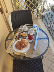 una mesa con una bandeja de bollería en el balcón en Ninfea Tropea City Rooms en Tropea