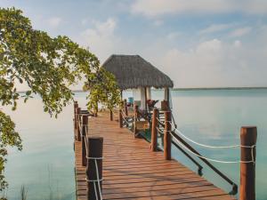 a dock with a hut on the water at Khaban Bacalar Hotel Boutique in Bacalar