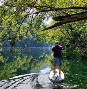 un hombre parado en una tabla de surf de remo en el agua en Štulceva Hiša, en Most na Soči