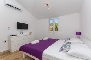 een witte slaapkamer met een bed en een televisie bij Apartment Rivendell in Dubrovnik