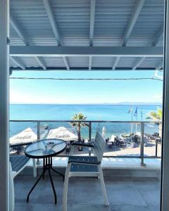 einen Balkon mit einem Tisch, Stühlen und Meerblick in der Unterkunft Myrto Rooms in Pefkohori