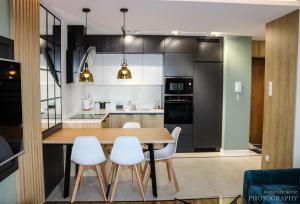 a kitchen with a wooden table and white chairs at D Apartments Centrum Prowiantowa II in Białystok