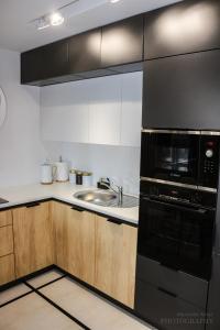 a kitchen with black appliances and a sink at D Apartments Centrum Prowiantowa II in Białystok