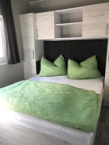sypialnia z łóżkiem z zieloną pościelą i poduszkami w obiekcie 3V Holiday Resort w mieście Drage