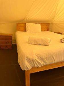a bedroom with a bed with a wooden headboard and white sheets at Tipi - Pengarreg in Aberystwyth
