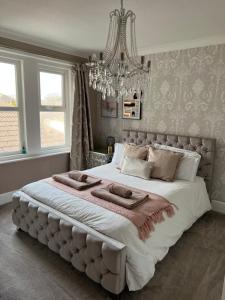 a large bed in a bedroom with a chandelier at Spacious 4 Bed Rooms, Parking, Garden and Near Parks, Beaches and University in Bournemouth