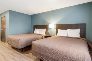 two beds in a room with blue walls at WoodSpring Suites Greensboro - High Point North in Greensboro