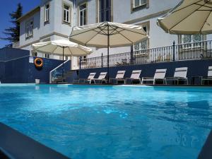 ein großer Pool mit Stühlen und Sonnenschirmen in der Unterkunft Hotel Villa Garden Braga in Braga