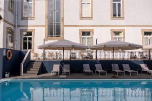 einen Pool mit Stühlen und Sonnenschirmen neben einem Gebäude in der Unterkunft Hotel Villa Garden Braga in Braga