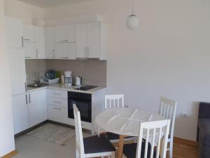 a kitchen with white cabinets and a table and chairs at Apartman A3 in Ulcinj