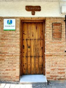 eine Holztür auf einem Backsteingebäude mit einem Schild in der Unterkunft Casa Chica in Cazorla