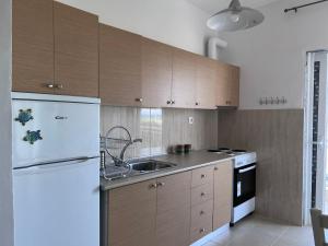 cocina con armarios de madera y nevera blanca en Aqua Theros Apartments, en Paralia Dionisiou