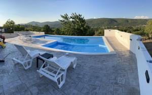 a swimming pool with two chairs and a table at Villa Green Hill, Cista Velika, Imotski in Omiš