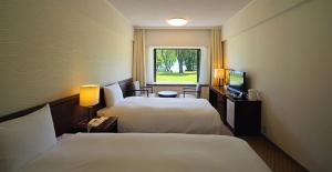 a hotel room with two beds and a window at Towada Prince Hotel in Kosaka