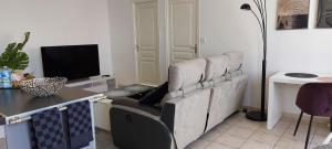 a living room with a couch and a desk with a television at Le CONTI Proche Roissy - Astérix- Gare in Le Plessis-Belleville