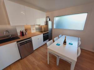 una cocina con una mesa blanca con una botella de vino. en La Volcane - Maison au calme des Bois Royaux en Le Chesnay