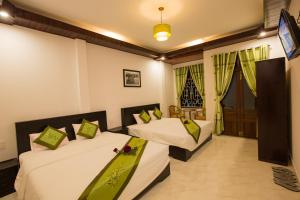 2 camas en una habitación de hotel con TV en The Village Homestay, en Hoi An