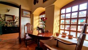 a dining room with a wooden table and windows at Hacienda San Isidro De Iltaqui in Cotacachi