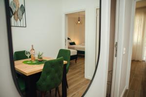 Zimmer mit einem Tisch und grünen Stühlen sowie einem Schlafzimmer. in der Unterkunft Baia di Cattaro in Kotor