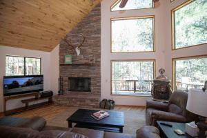 sala de estar con chimenea de piedra y muebles de cuero en The Duke Cabin - A FOREST LAKES Cabin in the Woods!, en Forest Lakes Estates