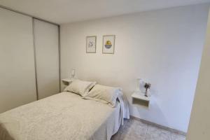 a white bedroom with a bed and two tables at BAITA dpto. B° Gral. Paz moderno y bien ubicado. in Córdoba