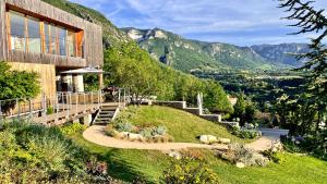 uma casa numa colina com montanhas ao fundo em Suites & Balnéo chez l'habitant - Vue panoramique sur le Vercors em Pont-en-Royans