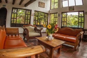 a living room with couches and tables and windows at Hotel Termales El Batan in Cuítiva