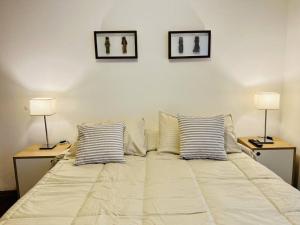 a large white bed with two lamps on two tables at Luminoso departamento con vista! in Cordoba