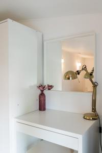 biała półka z lampą i lustrem w obiekcie Orchideen Apartment w Villach