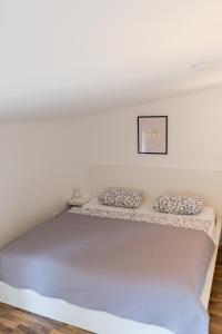 białe łóżko z dwoma poduszkami w obiekcie Orchideen Apartment w Villach