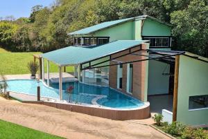 a house with a swimming pool in front of it at Pousada Trem Chic in Poços de Caldas