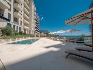 a swimming pool with chairs and umbrellas next to a building at CASA AL MARE RESIDENCE in Bečići