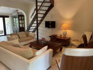 uma sala de estar com mobiliário branco e uma escadaria em Cunucu Jucasa em Noord
