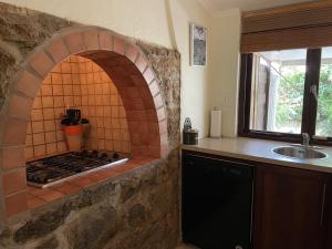 uma cozinha com um forno de tijolo e um lavatório em Cunucu Jucasa em Noord