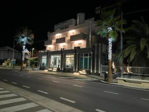un bâtiment avec des palmiers sur le côté d'une rue dans l'établissement Hotel Alb's, à Alba Adriatica